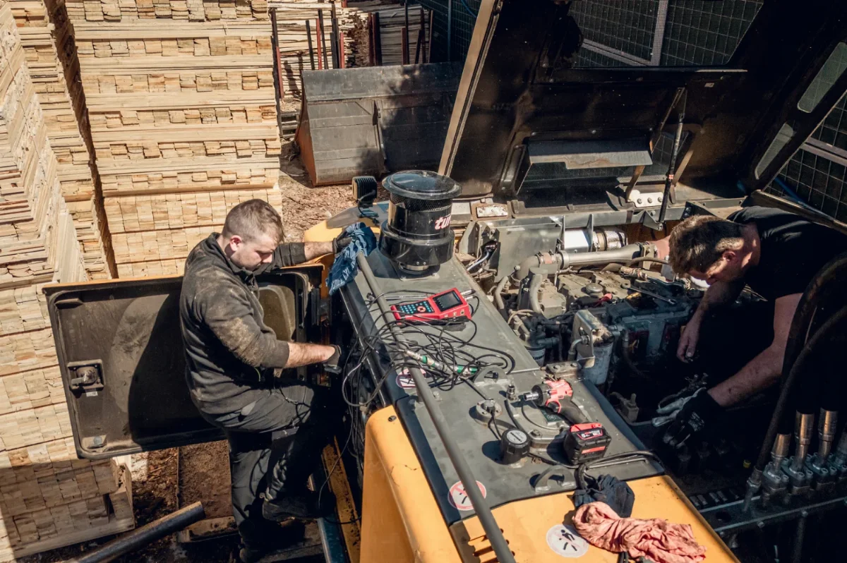 Monteure bei Diagnose und Reparatur eines Baumaschinenmotors im Feld