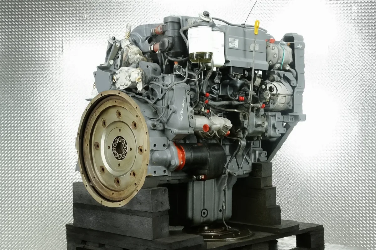 Vierzylinder-Motor von Liebherr auf einer Palette, Ansicht von der Schwungradseite mit Kraftstofffiltern und Anbauteilen