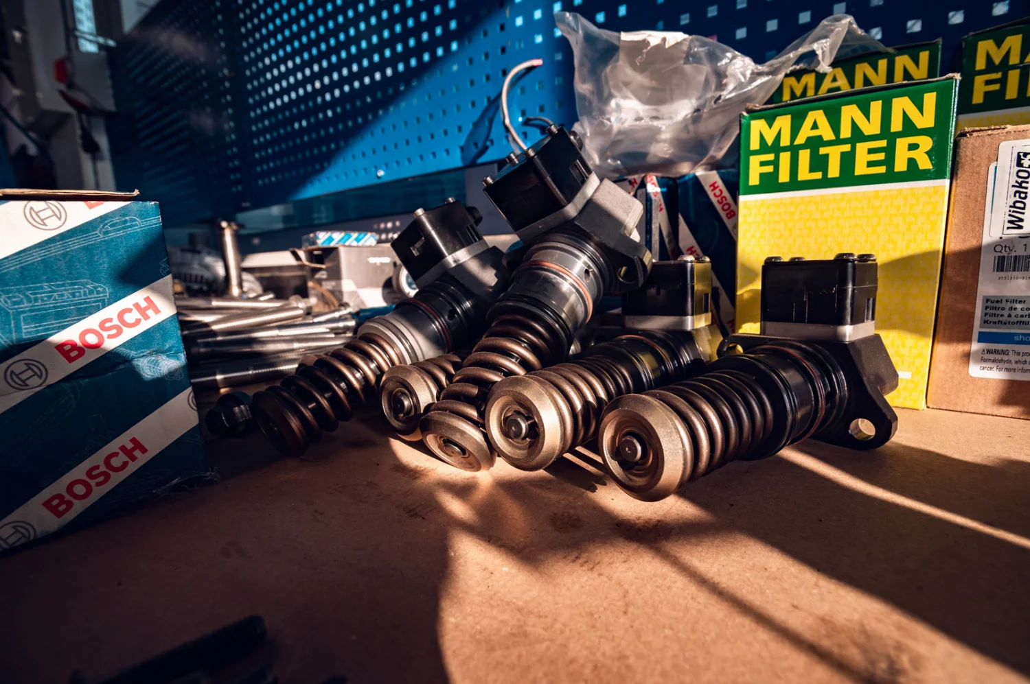 Pumpe-Düse-Einheiten eines Dieselmotors neben Bosch-Kartons und Mann-Filter-Verpackungen