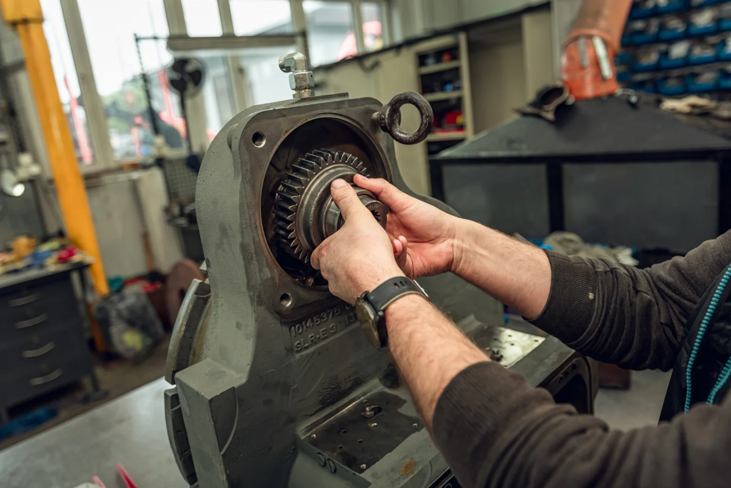 Mechaniker setzt ein Zahnrad in ein Getriebegehäuse bei der Überholung in der Werkstatt ein