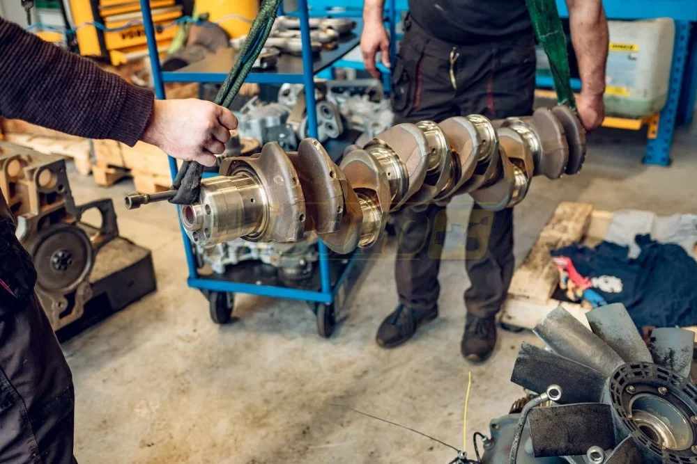 Kurbelwelle eines Dieselmotors an Transportgurten in einer Werkstatt für Motoreninstandsetzung