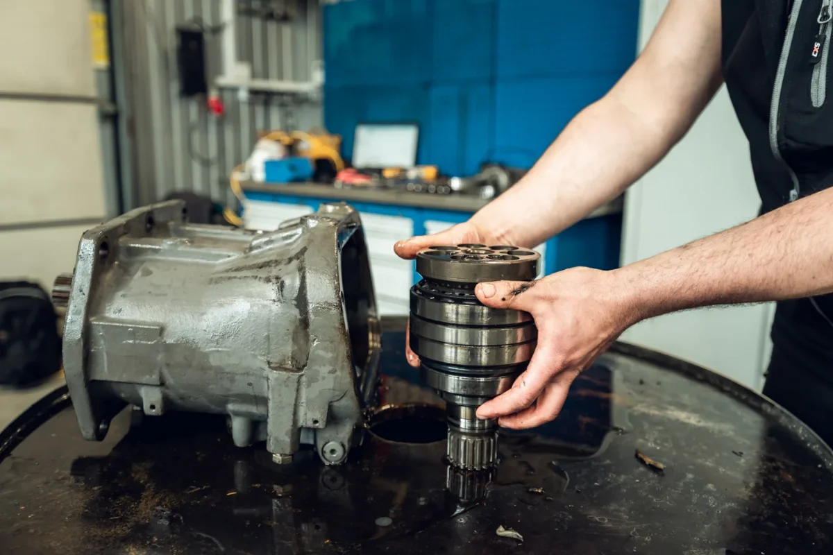 Mechaniker hält ein Triebwerk mit Keilwelle neben dem Gehäuse einer hydraulischen Kolbeneinheit