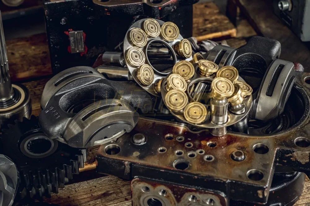 Zerlegte Axialkolben-Hydraulikpumpe: Kolben mit Messing-Gleitschuhen, Rückzugplatte und Wippen zur Prüfung vorbereitet